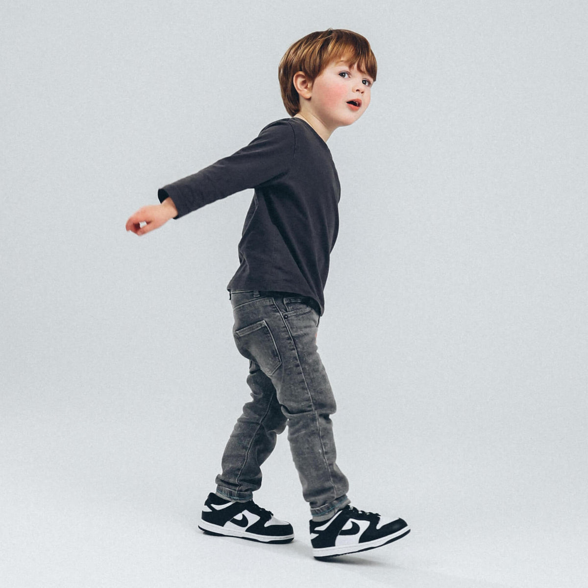 Enfant portant des sneakers Nike Dunk Low Panda avec un jean gris